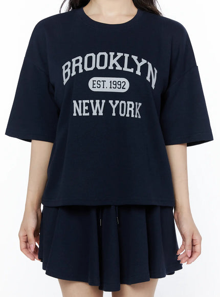 Brooklyn Grahic Tee & Mini Skort Set IU525 Dark blue front close-up on model showing Brooklyn EST.1992 New York graphic print on oversized cropped tee