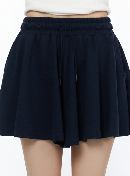 Brooklyn Grahic Tee & Mini Skort Set IU525 Dark blue close-up front detail of mini skort showing elastic drawstring waistband and pleated flared hem