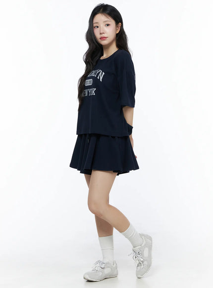 Brooklyn Grahic Tee & Mini Skort Set IU525 Dark blue three-quarter side view on model standing with hand in pocket, full outfit showing skort silhouette