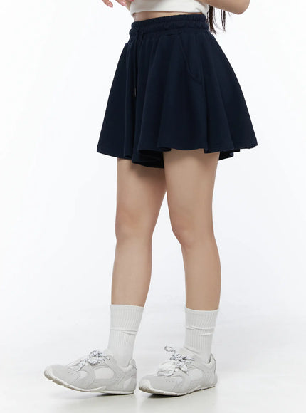 Brooklyn Grahic Tee & Mini Skort Set IU525 Dark blue lower-body side shot on model showing pleated skort volume and flared silhouette with sneakers