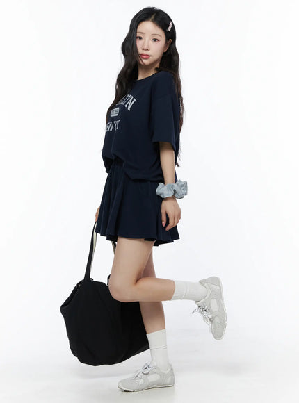 LEWKIN Brooklyn Grahic Tee & Mini Skort Set IU525 Dark blue side view on model styled with tote bag and sneakers, cropped boxy tee with collegiate graphic