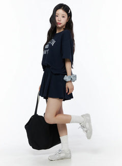 LEWKIN Brooklyn Grahic Tee & Mini Skort Set IU525 Dark blue side view on model styled with tote bag and sneakers, cropped boxy tee with collegiate graphic