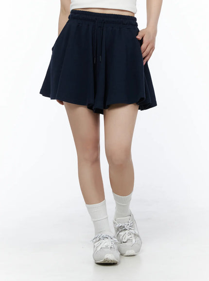Brooklyn Grahic Tee & Mini Skort Set IU525 Dark blue lower-body front shot on model showing flared mini skort with drawstring waist, white socks and sneakers