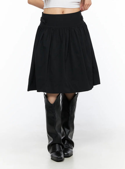 Buckle Midi Skirt CL517 Black front close-up model shot highlighting wide high-rise waistband, gathered pleats, and A-line flare with cowboy boots