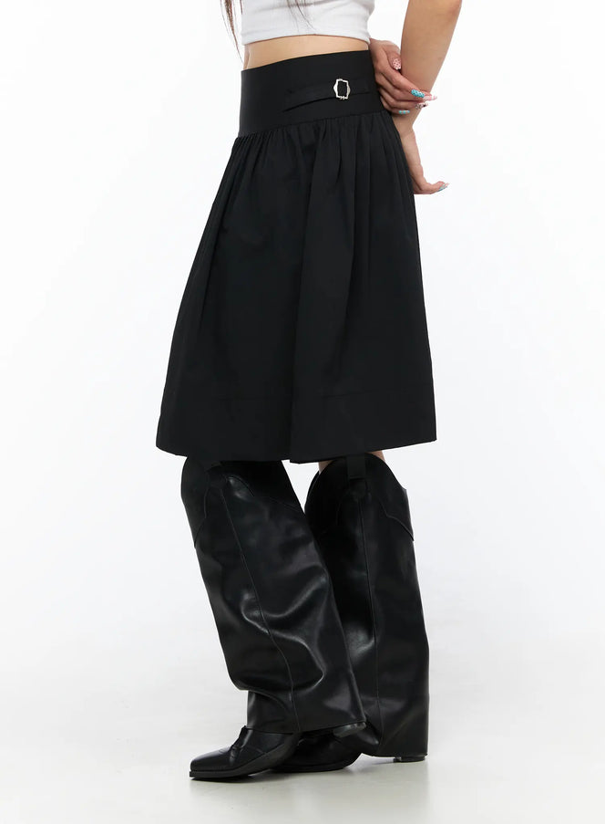 Buckle Midi Skirt CL517 Black side model shot showing wide waistband with silver buckle detail and gathered A-line silhouette with black boots