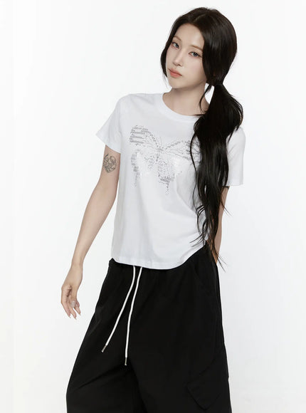 Butterfly Graphic Crop Tee IL521 White front view on model with side ponytail showing silver butterfly rhinestone graphic styled with black wide-leg drawstring pants