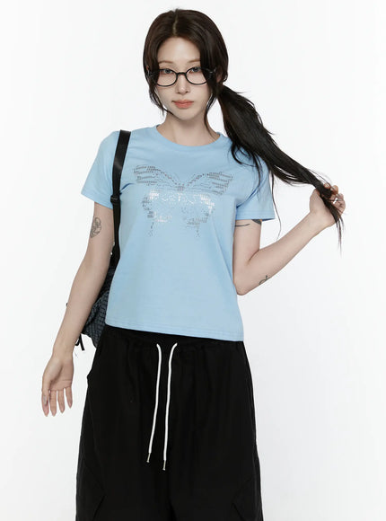 LEWKIN Butterfly Graphic Crop Tee IL521 Light blue front view on model wearing glasses and ponytail styled with black wide-leg pants and backpack
