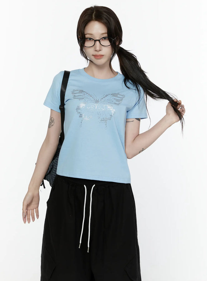 LEWKIN Butterfly Graphic Crop Tee IL521 Light blue front view on model wearing glasses and ponytail styled with black wide-leg pants and backpack