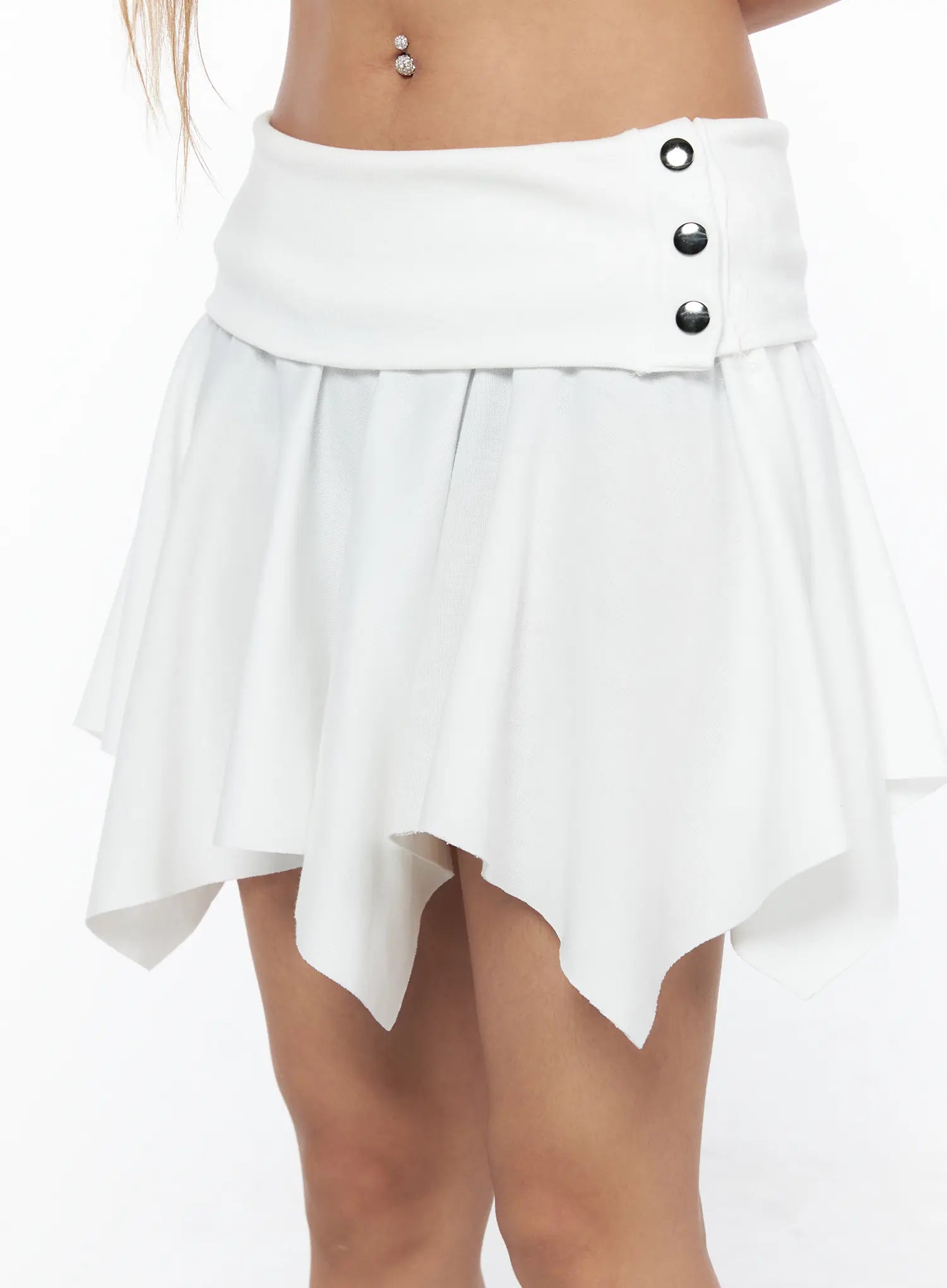 Button Flare Mini Skirt CU524 White close-up detail shot on model showing silver snap buttons on wide folded waistband and asymmetric pleated hem