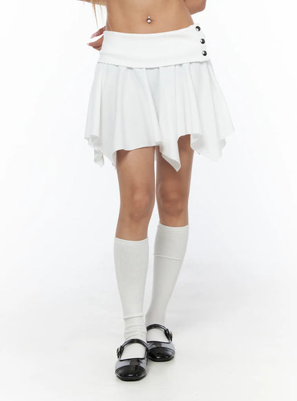 Button Flare Mini Skirt CU524 White close-up front shot on model showing folded waistband, silver button detail, and asymmetric handkerchief hem