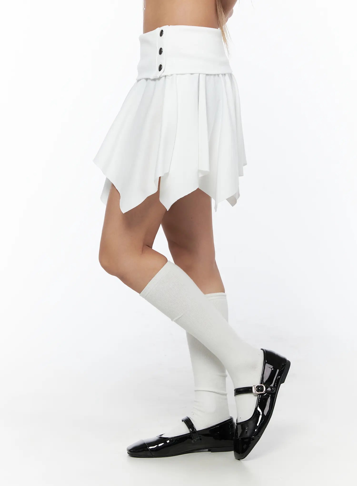 Button Flare Mini Skirt CU524 White side shot on model highlighting asymmetric draped hem, pleated skirt panel, and button waistband detail