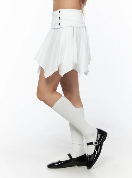Button Flare Mini Skirt CU524 White side shot on model highlighting asymmetric draped hem, pleated skirt panel, and button waistband detail