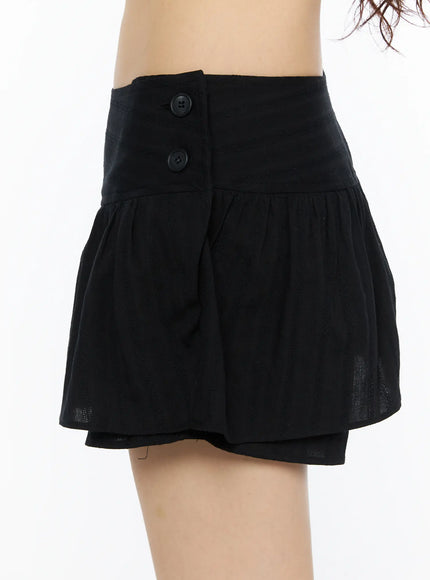 Button Flare Mini Skirt CU530 Black close-up side shot on model showing two-button detail, wide waistband, and gathered flare hem texture