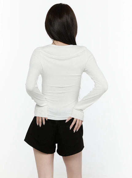 Button-Up Long Sleeve Top IL521 White back shot on model with hands on hips, showcasing smooth fitted back panel and long sleeves with cuff detail, paired with black shorts