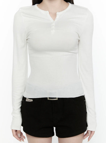 Button-Up Long Sleeve Top IL521 White close-up front torso shot on model, highlighting henley button placket, ribbed texture, and slim waist-defining fit over black mini shorts
