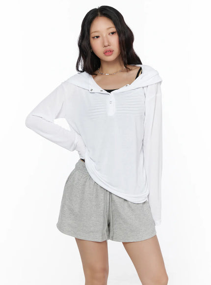 Button-Up Sheer Hoodie Top CL513 White front view on model standing with snap button placket hood down layered over black striped cami and gray shorts