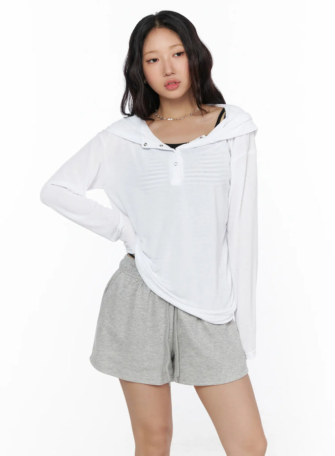 Button-Up Sheer Hoodie Top CL513 White front view on model standing with snap button placket hood down layered over black striped cami and gray shorts