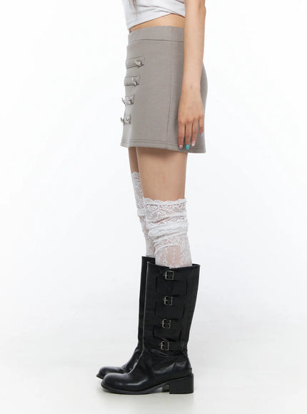 Buttoned Mini Skirt CL517 Beige side shot on model revealing silver button trim along skirt edge styled with lace knee socks and boots