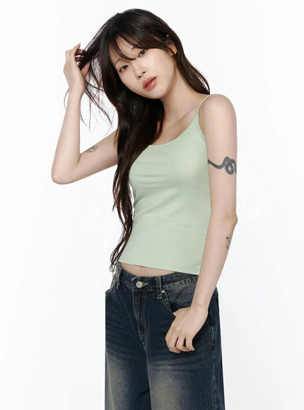 Cami Tank Top IL506 Mint three-quarter front shot on model touching hair, cropped ribbed top with spaghetti straps, styled casually with wide-leg jeans