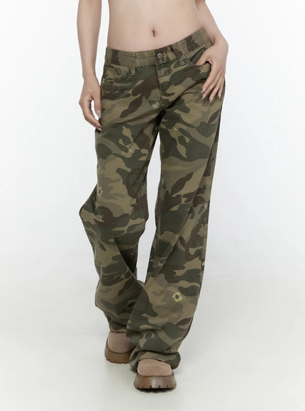 Camo Cargo Trousers IL522 Dark green front view on model hand in pocket, low-rise wide-leg camo pants with scattered floral motifs and chunky boots