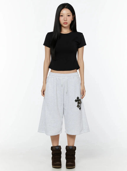 Camo Cross Patch Bermuda Shorts IU524 Light gray full-body front shot on model standing straight, styled with black crop tee and brown wedge sneakers, arms relaxed