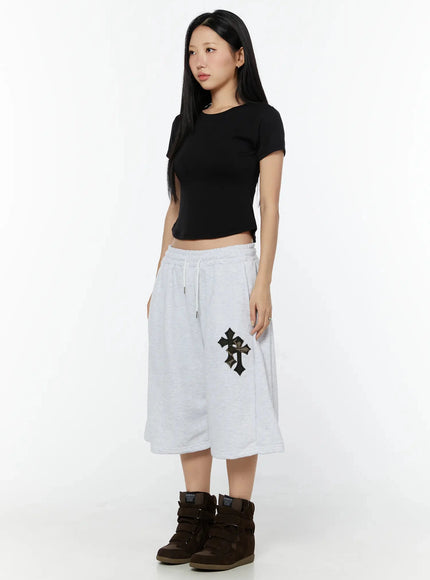 Camo Cross Patch Bermuda Shorts IU524 Light gray three-quarter side front view on model looking aside, paired with black crop tee and brown wedge sneakers
