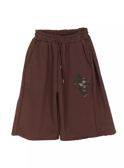 Camo Cross Patch Bermuda Shorts IU524 Brown flat-lay front view showing wide-leg silhouette, dark brown fleece fabric, elasticated drawstring waistband and camo cross appliqué patch