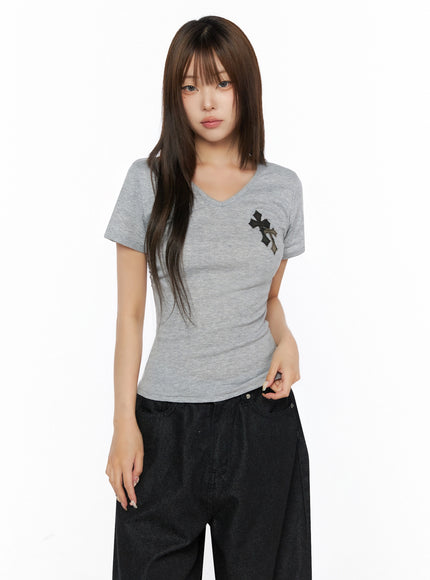 Camo Cross V-Neck Side Shirring Slim Tee IL515 Gray front model half-body shot, arms relaxed, cross patch detail on chest, slim ribbed knit, paired with black wide-leg pants