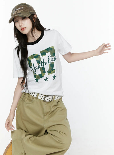 LEWKIN Camo Graphic T-Shirt IL522 White S/M front angled shot on model seated pose wearing camo cap black ringer neckline camouflage 07 Youth Era print