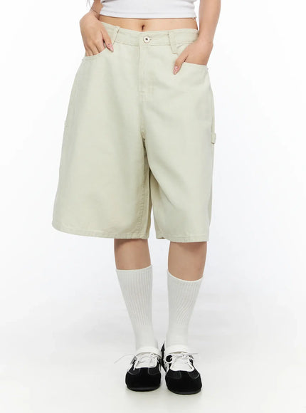Cargo Bermuda Shorts CL514 Light beige front close-up on model with hands in pockets, showing button closure, belt loops and wide waistband