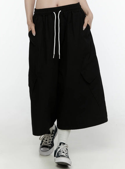 Cargo Pocket Shorts IL521 Black front shot on model hands in pockets showing elastic drawstring waist oversized cargo pockets and wide-leg cut