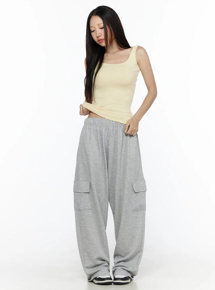 Cargo Wide Leg Sweatpants CL524 Gray full-body front shot on model looking down wearing yellow tank top pulling up waistband showing elastic waist and cargo pockets