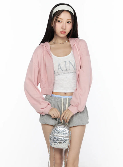 LEWKIN Casual Cropped Hoodie CL527 Light pink front shot on model size S/M open zip hoodie styled with graphic crop top and gray shorts holding silver quilted mini bag