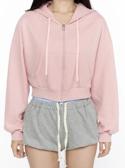 Casual Cropped Hoodie CL527 Light pink close-up detail shot on model showing front center zipper drawstring hood kangaroo pocket and ribbed waistband fleece texture