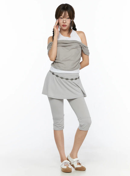 Casual Layered Halter Top CL517 Beige full-body front shot on model adjusting glasses layered draped top with chain belt mini skirt and cropped leggings