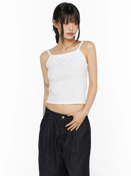 Casual Sleeveless Top CU530 White three-quarter front shot on model looking down, cropped spaghetti-strap camisole in ribbed knit paired with wide-leg dark denim trousers