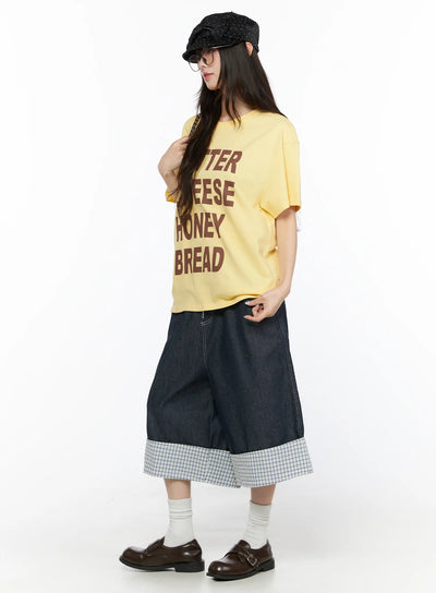 LEWKIN Check Back Pocket Jorts CL522 Dark blue M/L side view on model styled with yellow graphic tee, cap, and loafers showing wide-leg denim silhouette with plaid cuff hem