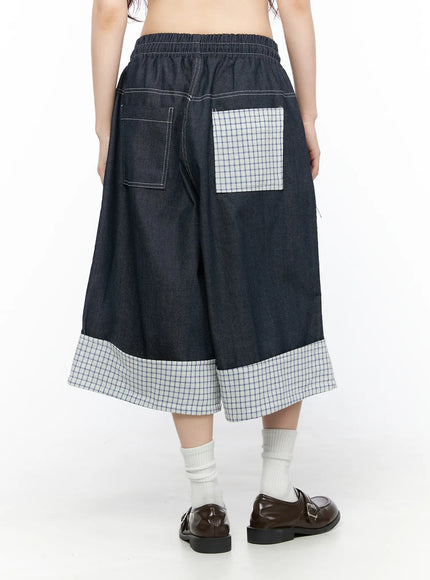 Check Back Pocket Jorts CL522 Dark blue back view on model showing elastic waistband, contrast white topstitching, denim left pocket and plaid patch right pocket with plaid cuff hem