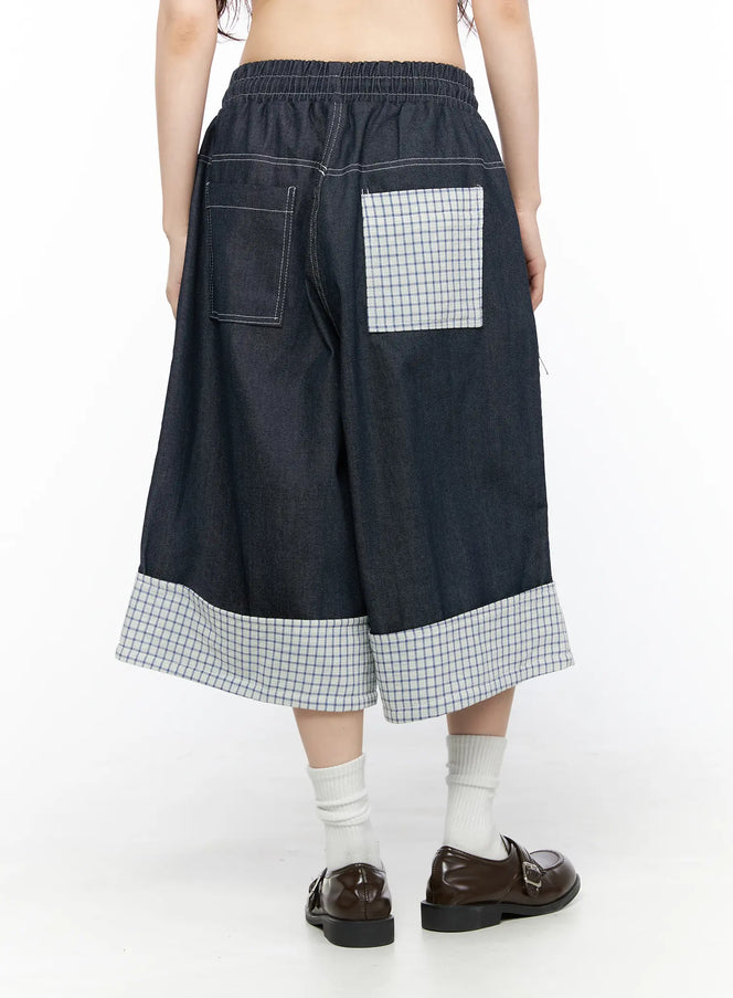 Check Back Pocket Jorts CL522 Dark blue back view on model showing elastic waistband, contrast white topstitching, denim left pocket and plaid patch right pocket with plaid cuff hem