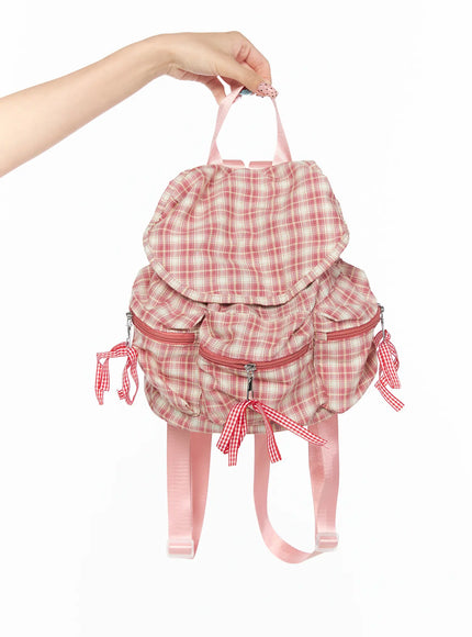 LEWKIN Checked Ribbon Backpack CL517 Pink front view held by hand showing plaid fabric ruffle flap gingham ribbon bows and pink straps