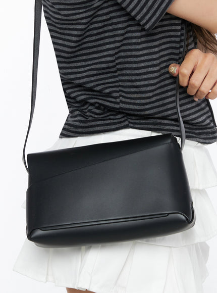 Classic Faux Leather Crossbody Bag IL523 Black close-up detail shot model gripping strap diagonal seam faux leather texture against striped top