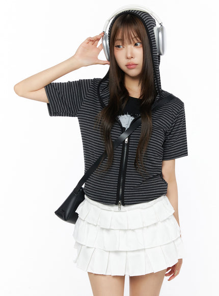 Classic Faux Leather Crossbody Bag IL523 Black front model shot half-body pose with hooded zip top white ruffle skirt and headphones