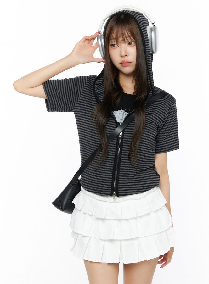 Classic Faux Leather Crossbody Bag IL523 Black front model shot half-body pose with hooded zip top white ruffle skirt and headphones