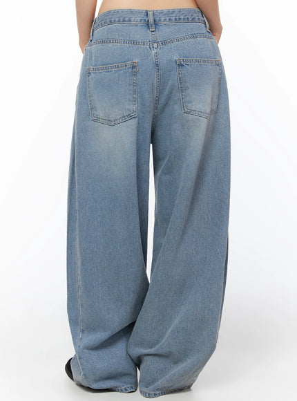 Coleen Side Pleat Baggy Jeans IL502 Blue full-body front shot on model wearing headphones cap and cream star-print tee with studded belt and chunky sneakers