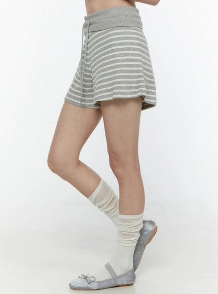 Colette Striped Banding Shorts IL506 Gray side shot on model from waist down leg raised showing flared striped hem drawstring and fold-over waistband with ballet flats and slouch socks