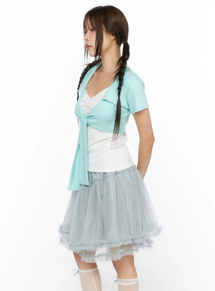 Collared Tie Short Sleeve Crop Bolero CL514 Mint side shot model hand in pocket wearing mint tie-front crop bolero over white top with layered gray tulle skirt and sheer socks