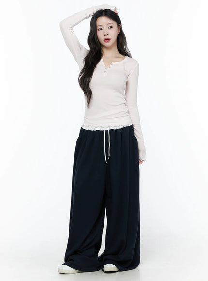 Color Contrast Wide-Leg Sweatpants IU525 Dark blue full-length front shot on model in cream ribbed top with arm raised, ultra-wide draped legs and white sneakers
