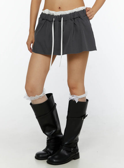 Contrast-Banded Low Rise Mini Skirt CL515 Dark gray front close-up on model showing white ruffle waistband white drawstring and flared silhouette