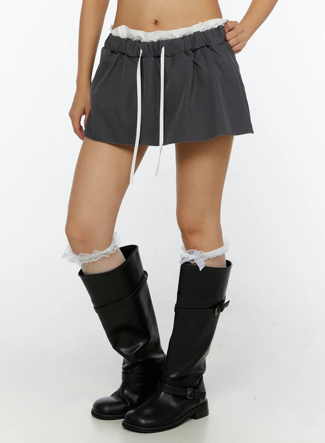 Contrast-Banded Low Rise Mini Skirt CL515 Dark gray front close-up on model showing white ruffle waistband white drawstring and flared silhouette