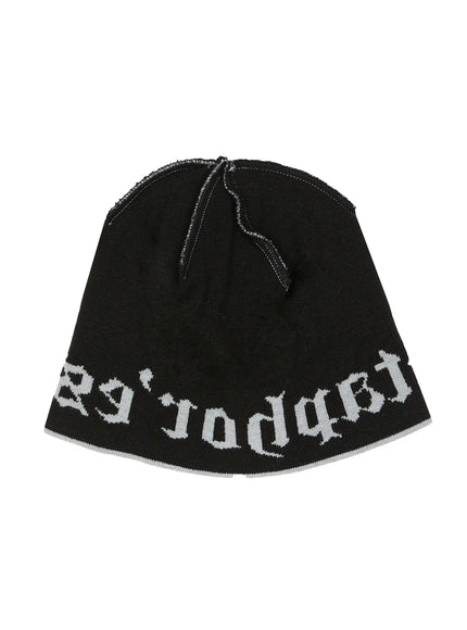 Contrast Graphic Text Reversible Beanie IL516 Black product flat shot, inside-out view showing white gothic text reversed on black knit fabric with raw crown seam